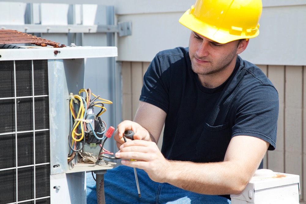 commercial hvac repair technician working on a wire