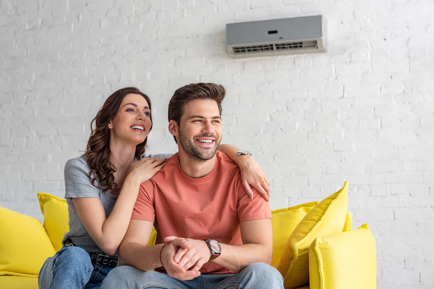 a happy couple enjoying their air conditioning unit